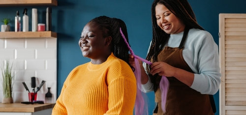 Black hairstylist creating a protective braided style
